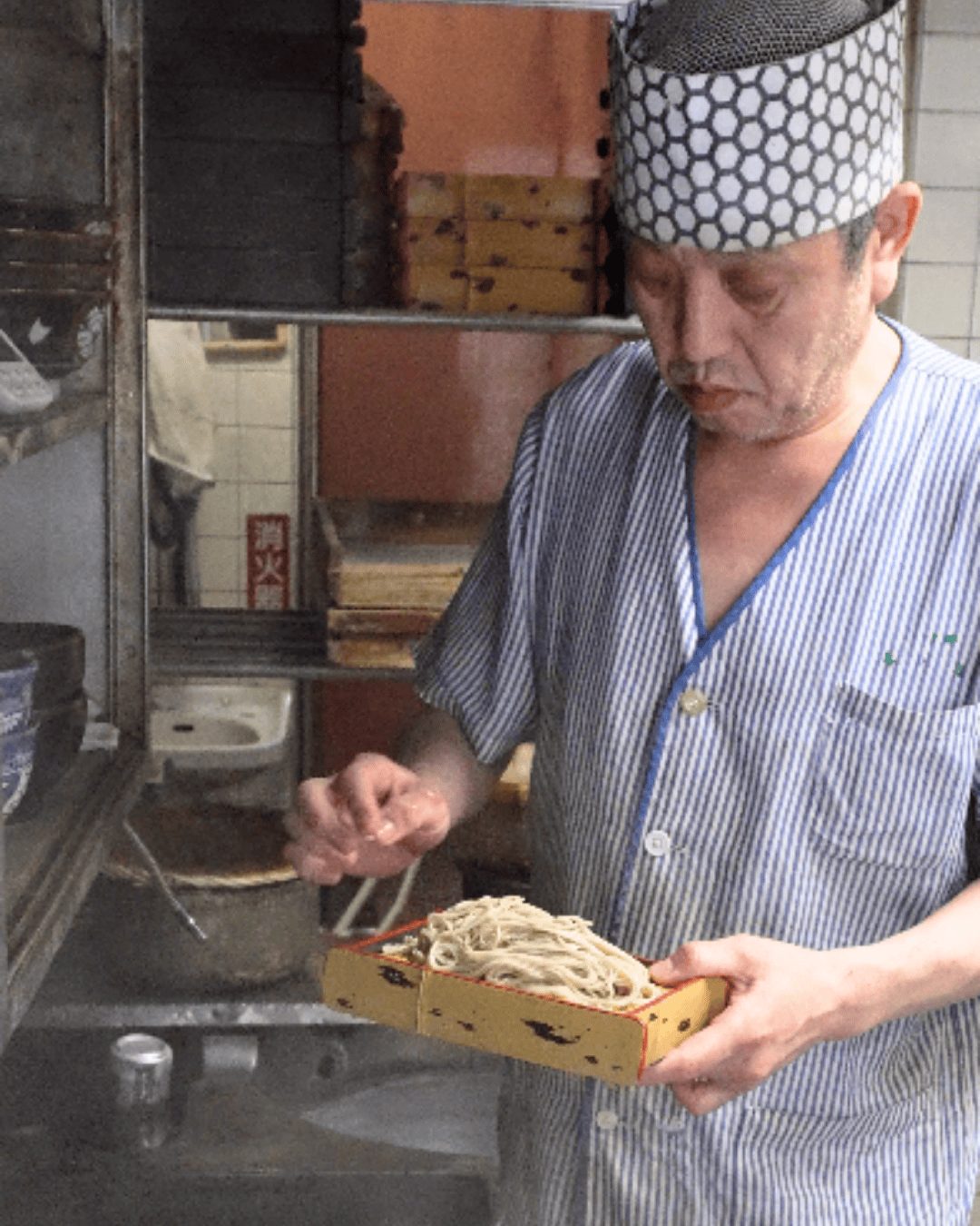 厨房で蕎麦を手にする3代目